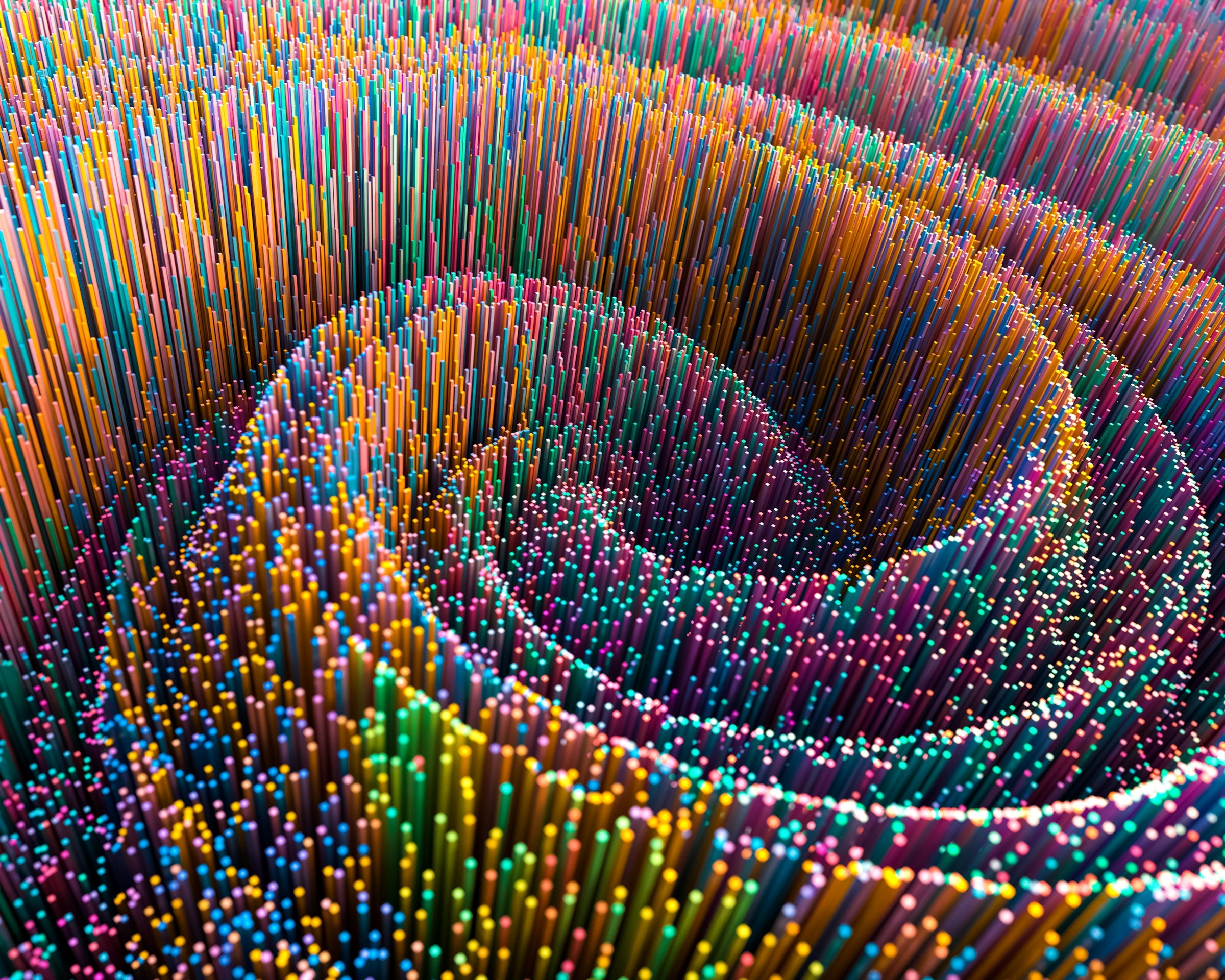 A spiral of thin multicolored rods winding toward a dark center